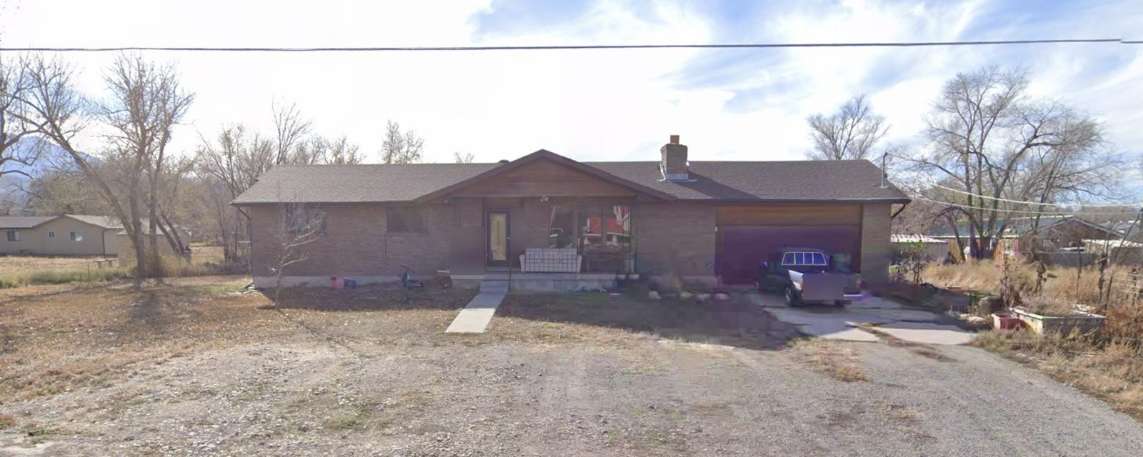 Before: front of the house with a gravel yard and concrete driveway