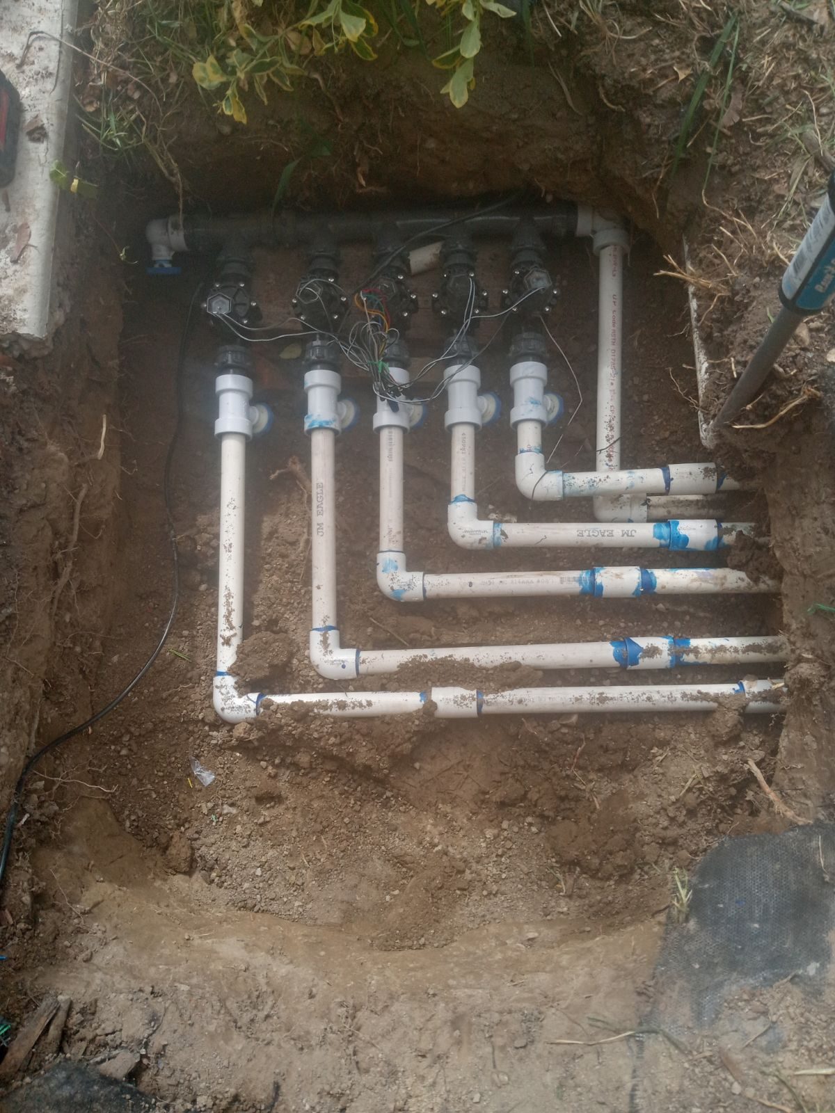 New sprinkler zone valves and PVC lines laid out for a Utah County yard