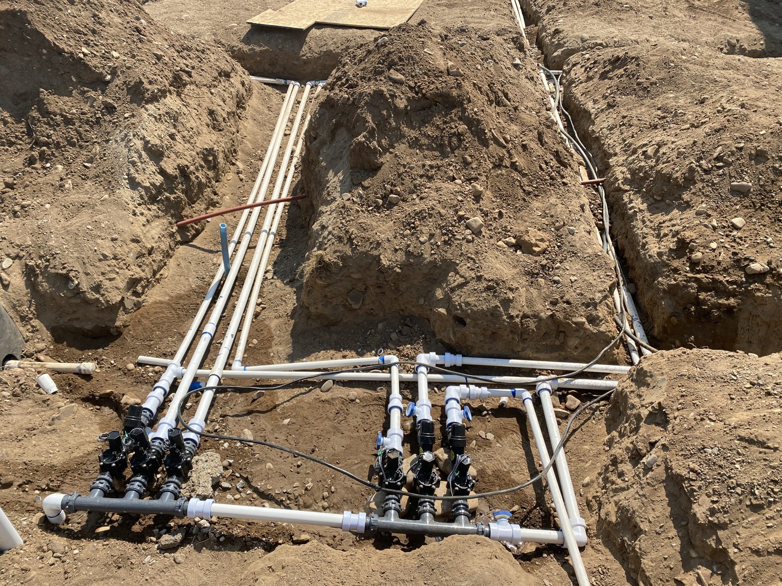 Two new sprinkler valve manifolds in a trench during a new system install