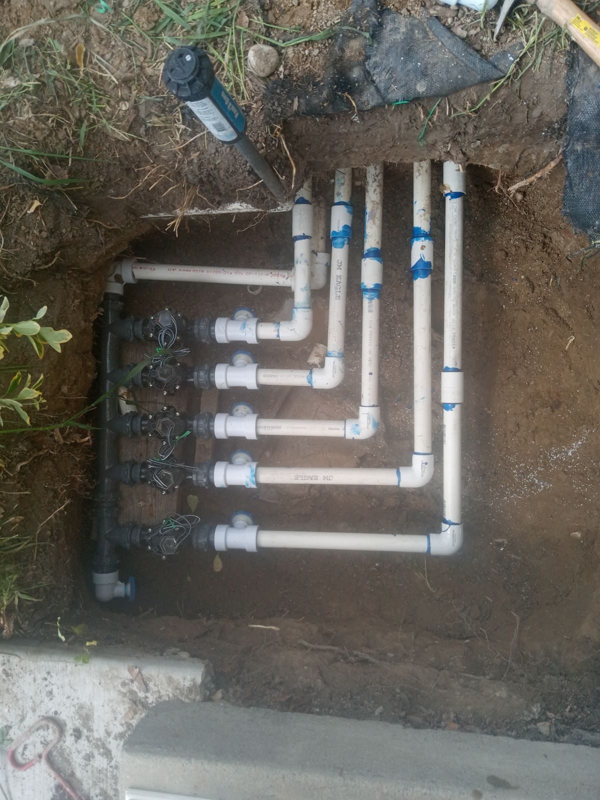 Overhead view of a new sprinkler valve manifold with PVC lines in Orem, UT