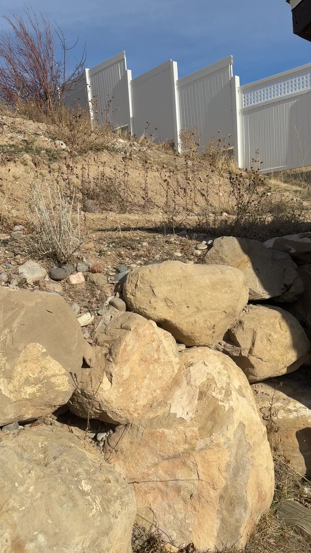 Before: steep dirt hillside with loose boulders below the fence