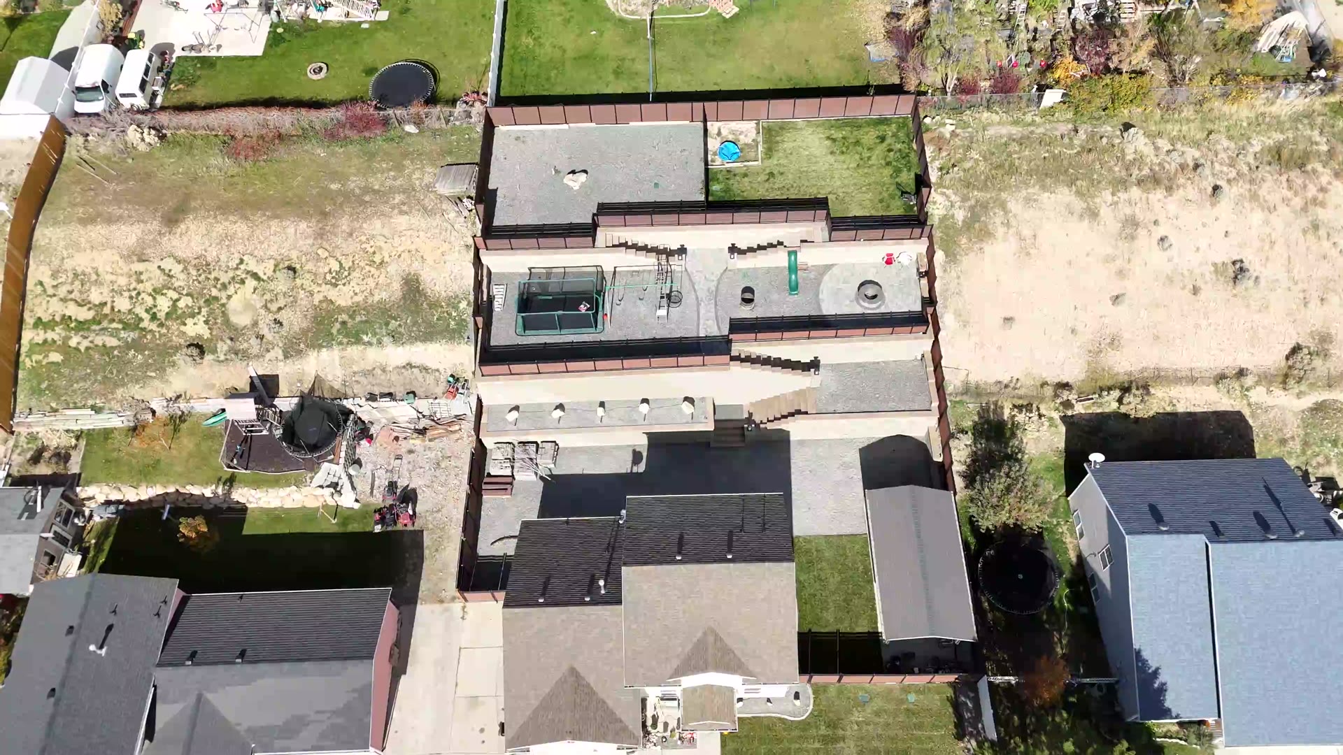 Overhead drone view of a finished three-tier block retaining wall with paver patio