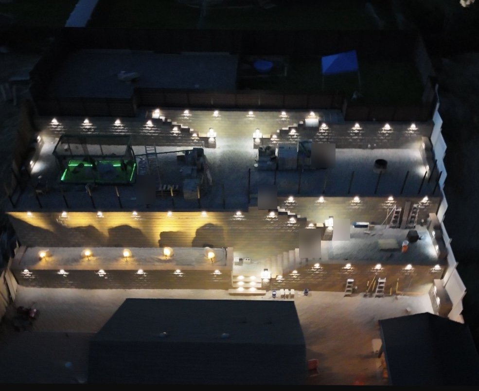 Three-tier block retaining wall lit by under-cap lights at night