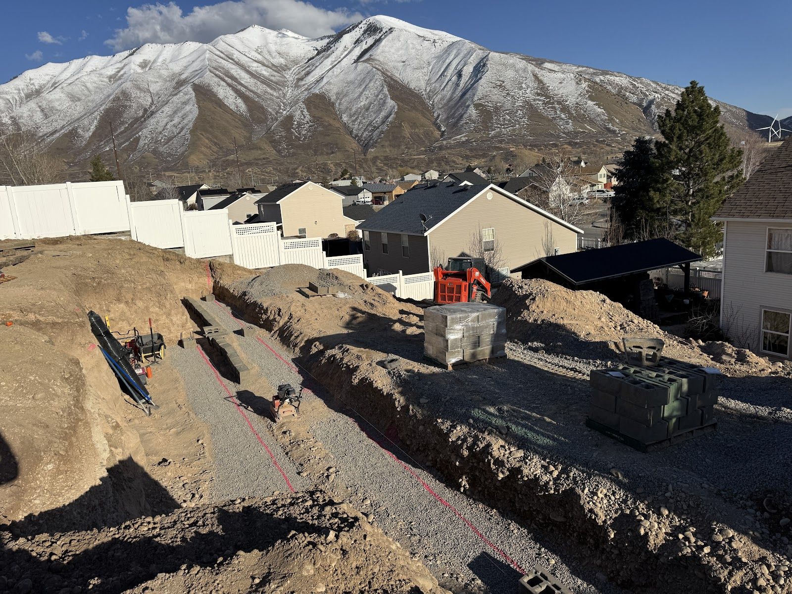 Excavated hillside with trenches cut for the retaining wall, mountains behind