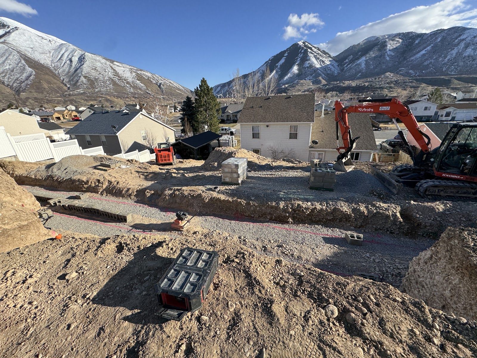 Excavator and block pallets on the graded backyard site