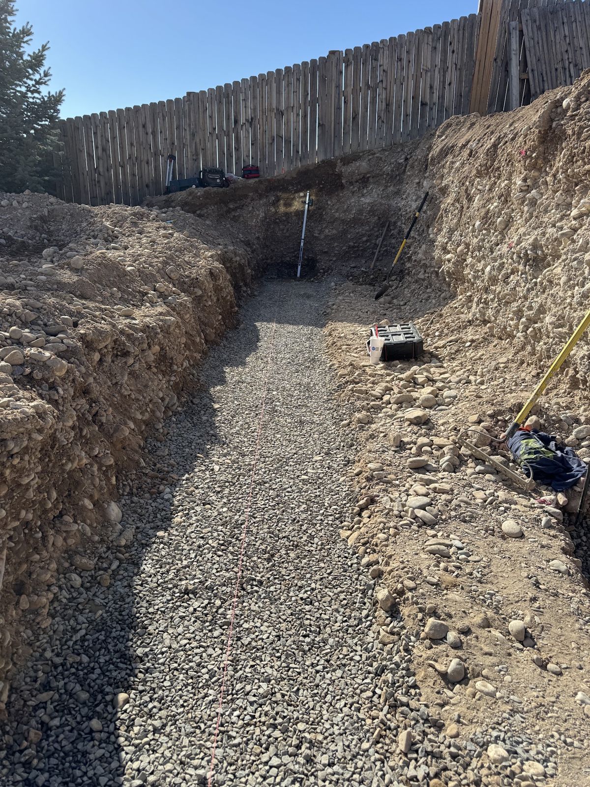Gravel-filled trench along the fence ready for the wall base
