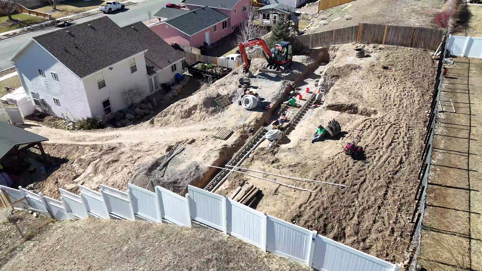 Overhead drone view of the excavation with excavator and trenches