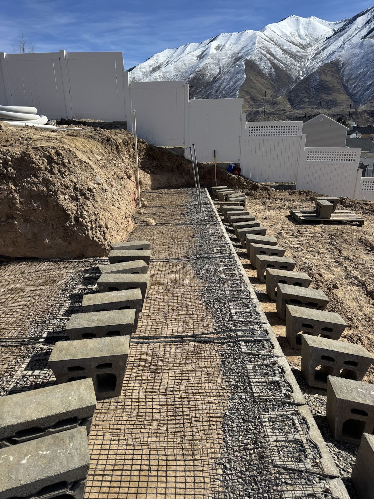 Block wall courses with geogrid laid across the gravel base